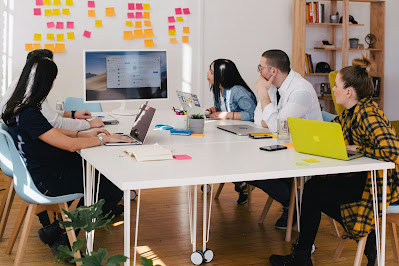 A group of people in a meeting watching a big monitor from the wall
